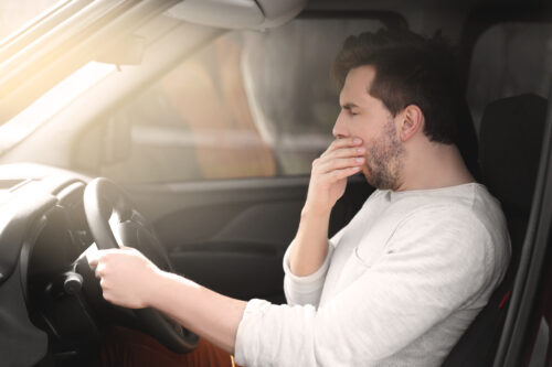 person behind the wheel fatigued driving yawning